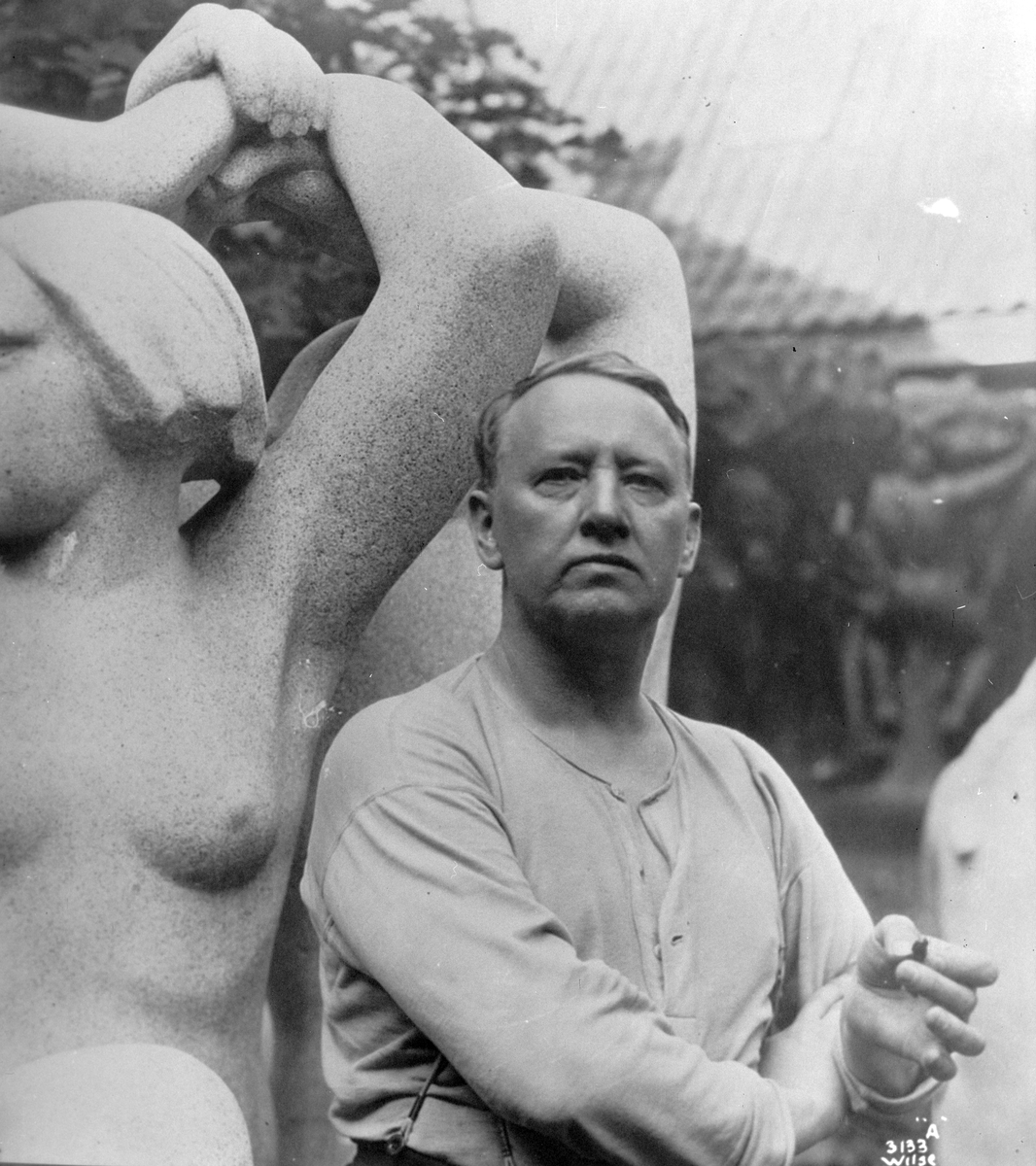 Portrett av Gustav Vigeland ved siden av en av sine skulpturer.