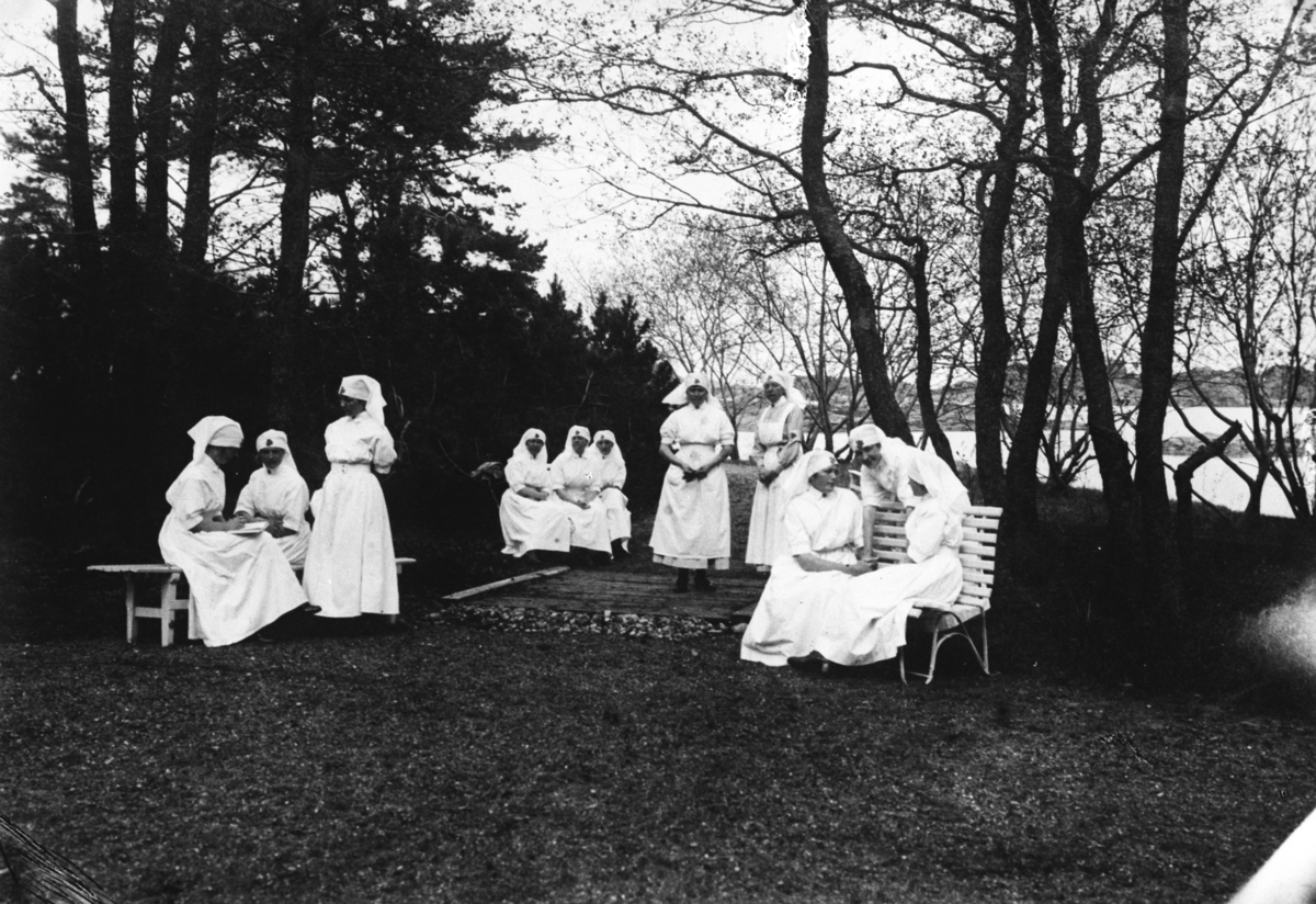 Kvinner fra Sanitesforeningen sitter på benker. Fotografert 1923.