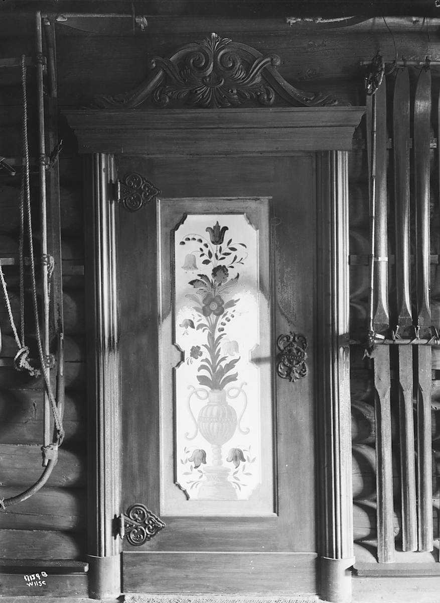 Dekorert dør, flere ski henger på siden, Titan & Co, Skimuseet. Fotografert 1923.