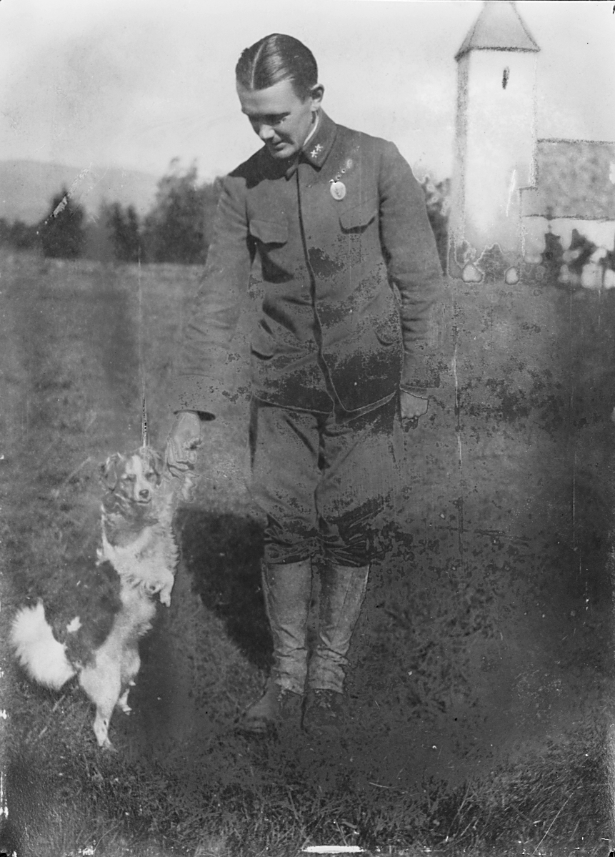 Mann i uniform med hund, kirke i bakgrunnen. Fotografert 1923.