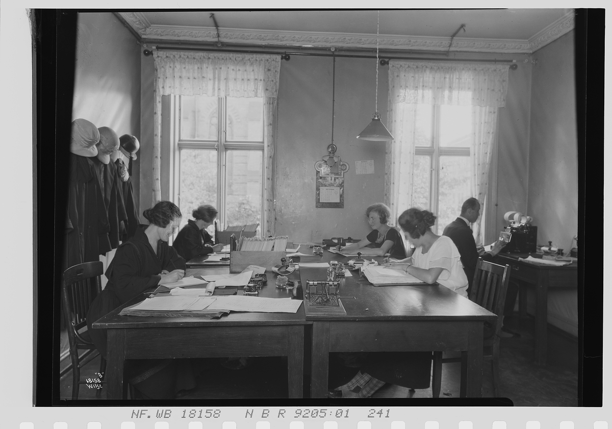 Kvinner og en mann sitter sammen på et kontor i avd. C, Vinmonopolet. Fotografert 1924.