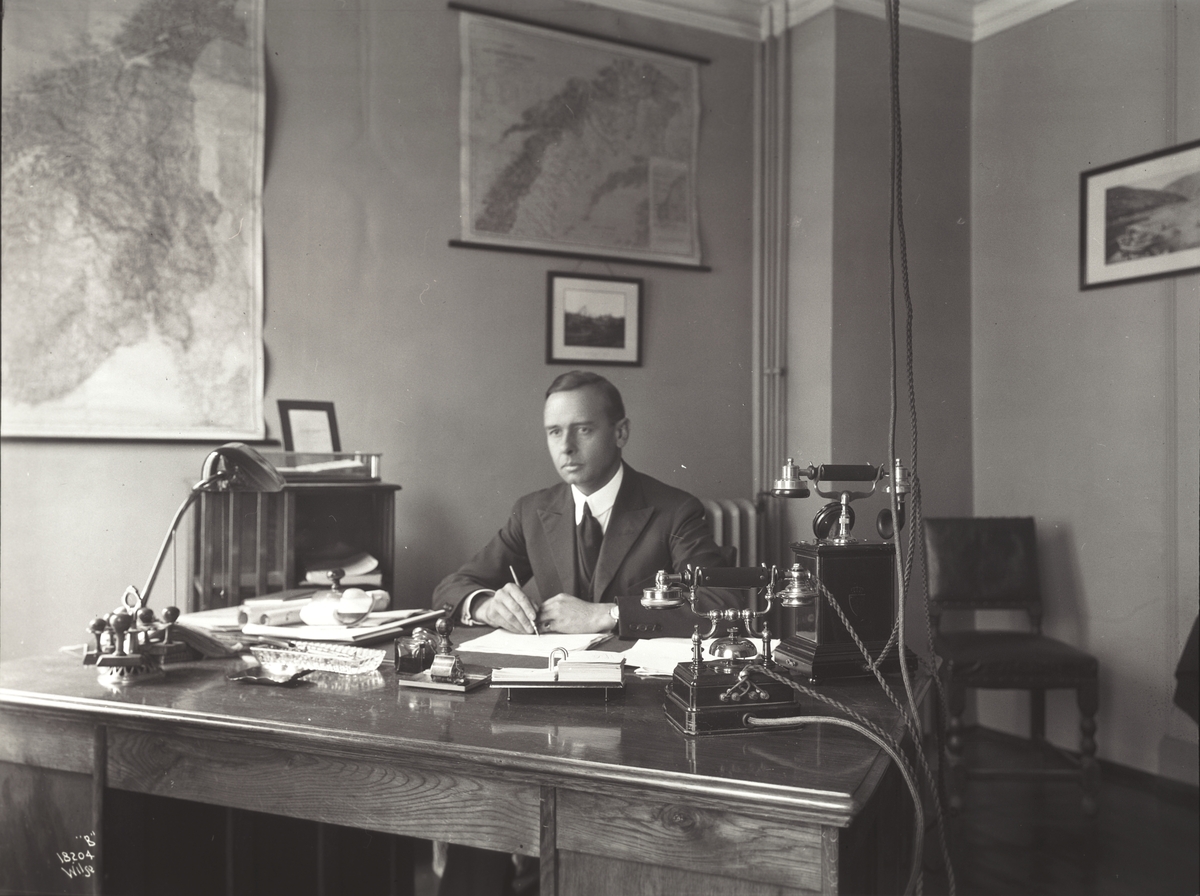 Mann sitter ved skrivebord. Fotografert 1924.