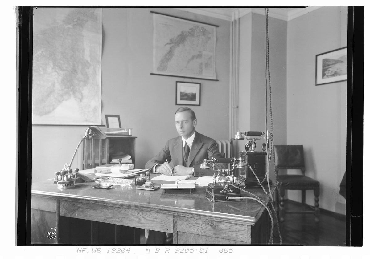 Mann sitter ved skrivebord. Fotografert 1924.