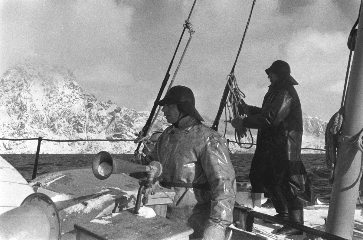 Redningsskøyten "Biskop Hvoslef" med mannskap patruljerer kysten, bratte fjell dekket av snø langs kyststripen.