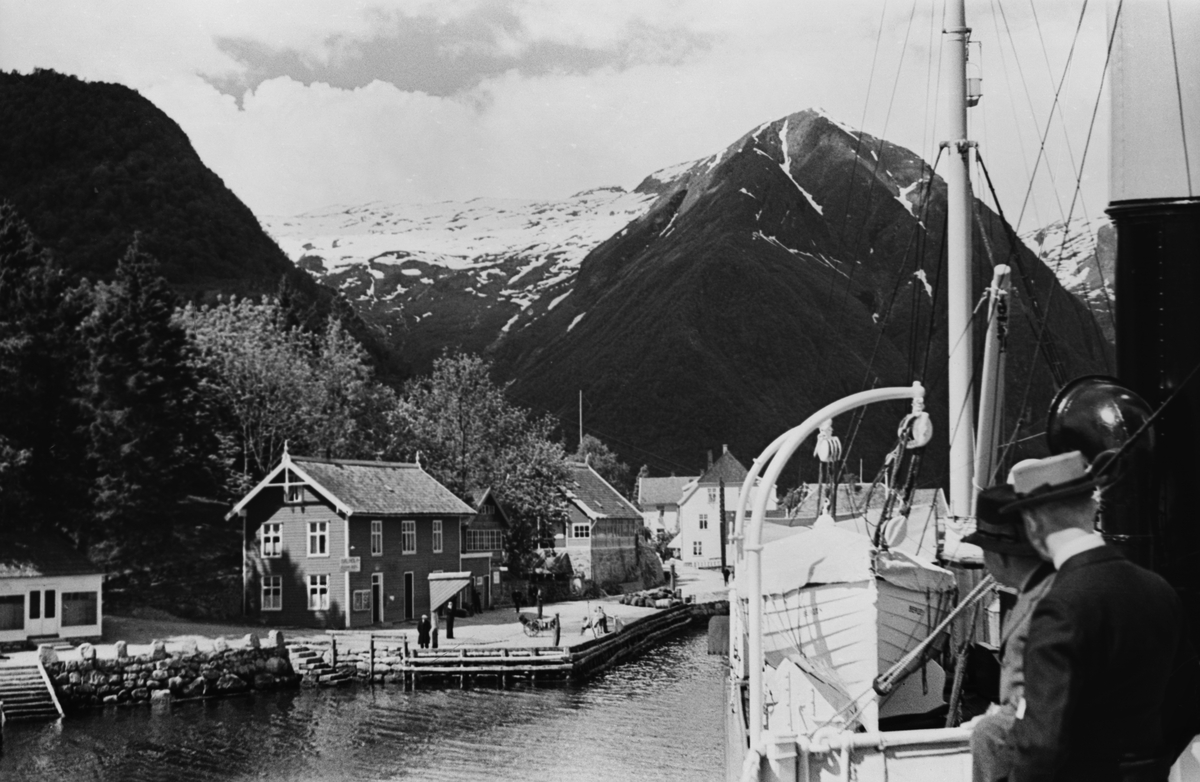 Anløpsted for fjordbåten, kai for ilandstigning, flere hus ved kaikanten.