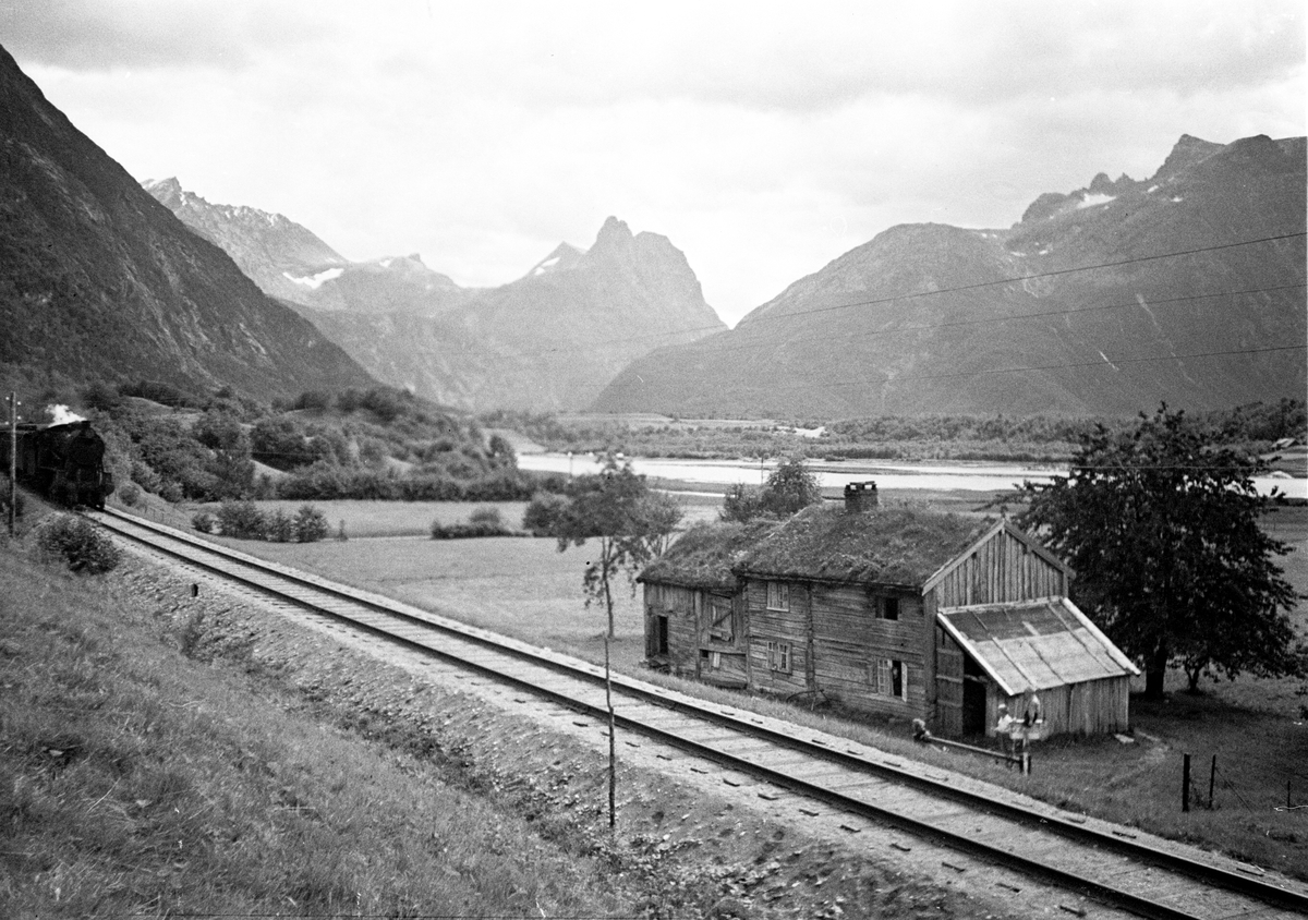 Romsdal, Raumabanen, skinnegangen passerer gammel gård med tømmerhus.