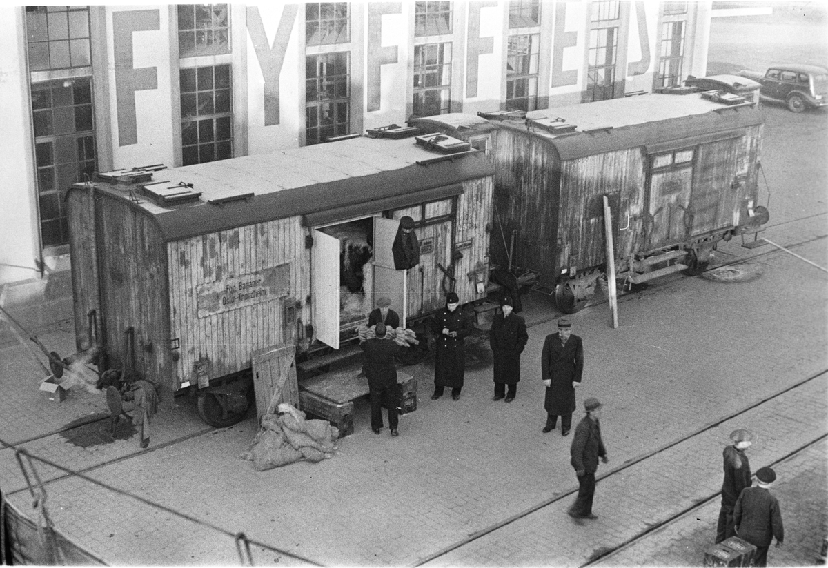 Oslo Havn, lessing og lossing fra to vogner på bryggen.  Kjøp og salg, politi på plass.  I bakgrunnen større lagerbygning