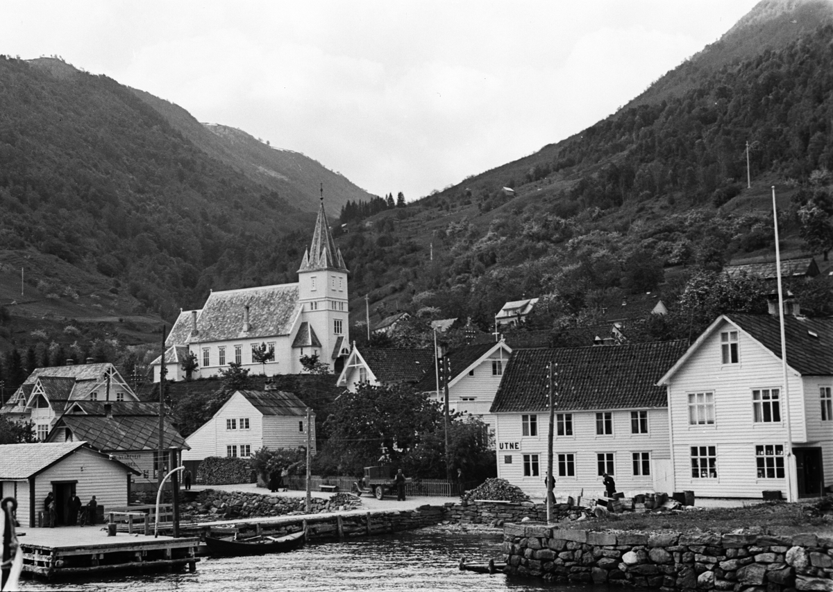 Utne kirke ligger vakkert til i høyden opp fra fjorden. Trehusbebyggelse dominerer stedet.