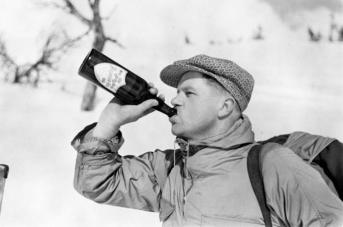 Påsketurist på ski tar seg en Pilsner-Øl. Fotografert 1940.