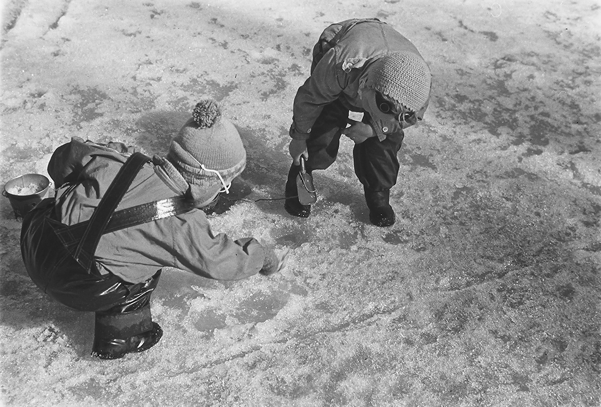 To barn som leker med bøtte og spade i snøen. Fotografert 1940.