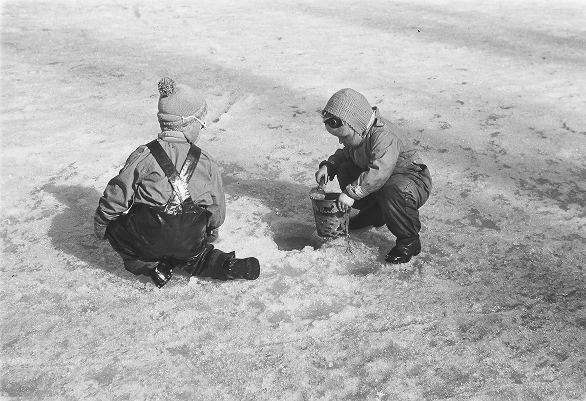 To barn som leker med bøtte og spade i snøen. Fotografert 1940.