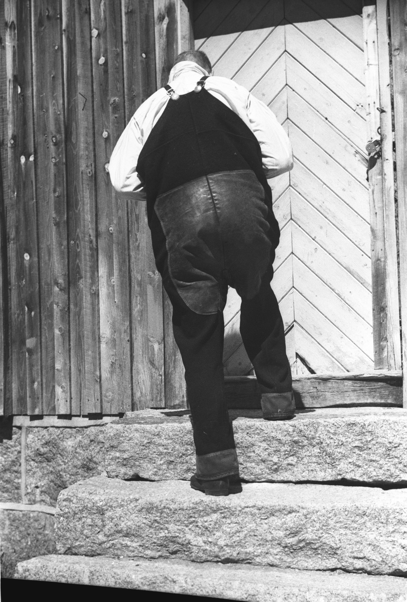 Storvokst kar i bunad, tar trappen opp til inngangsdøren.