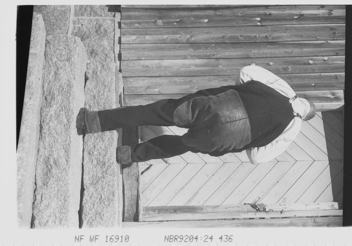 Storvokst kar i bunad, tar trappen opp til inngangsdøren.