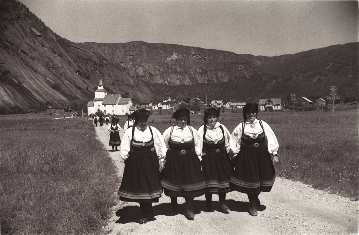 Bunadkledde setesdøler på vei fra kirke, en flott dag hvor solen skinner over kirkegjengere,  fjell og dal.