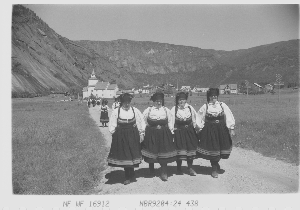 Bunadkledde setesdøler på vei fra kirke, en flott dag hvor solen skinner over kirkegjengere,  fjell og dal.