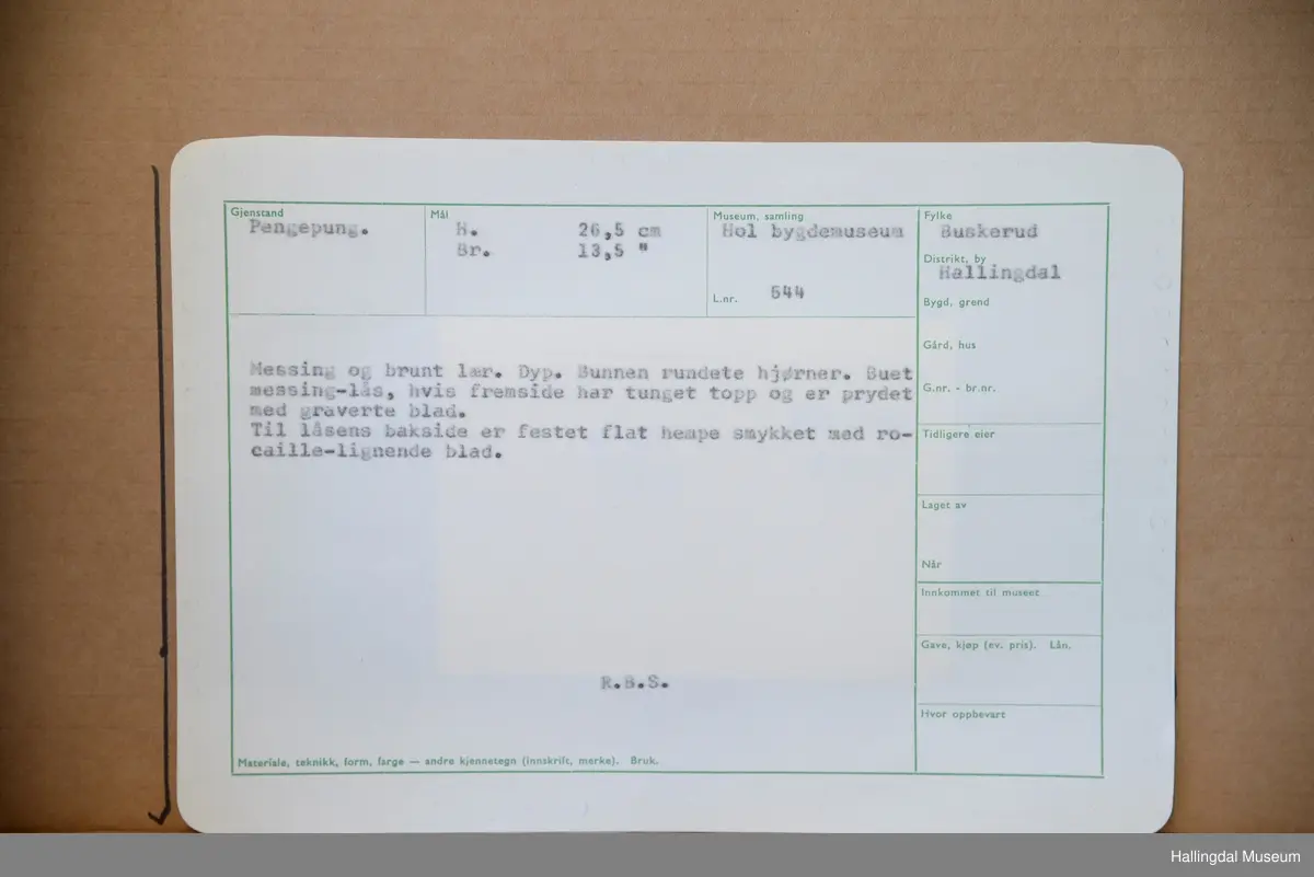 Dyp. Bunnen rundete hjørner. Buet messinglås, hvis framside har tunget topp og er prydet med gravert blad. Til låsens bakside er festet flat hempe smykket med rocaille lignende blad. R.B.S.