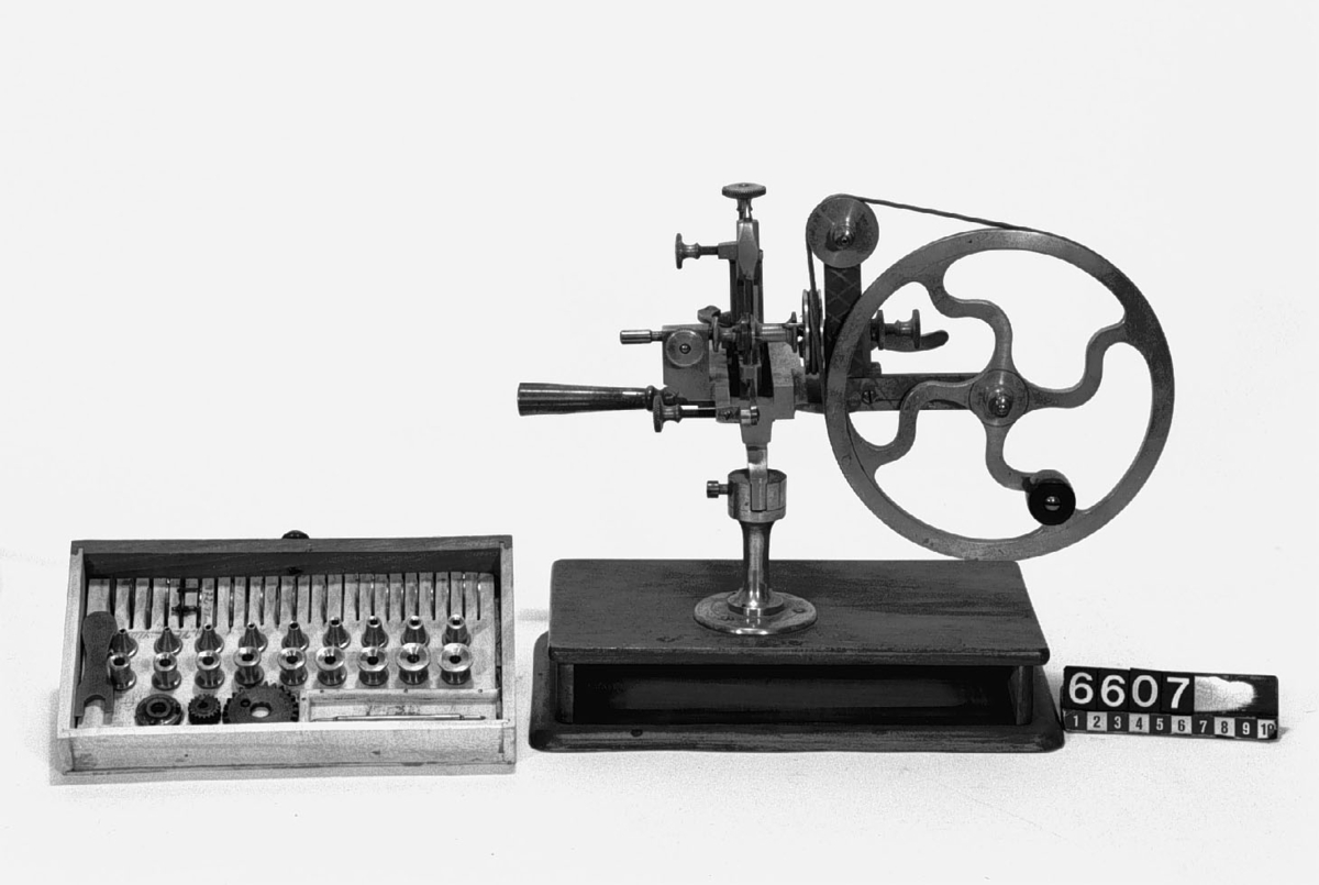 Kuggskärningsmaskin för hjul till klockor. Fotplattans längd: 255 mm, bredd: 160 mm. 47 st. lösa delar, varav 6 st. ursprungligen inte hör till apparaten.