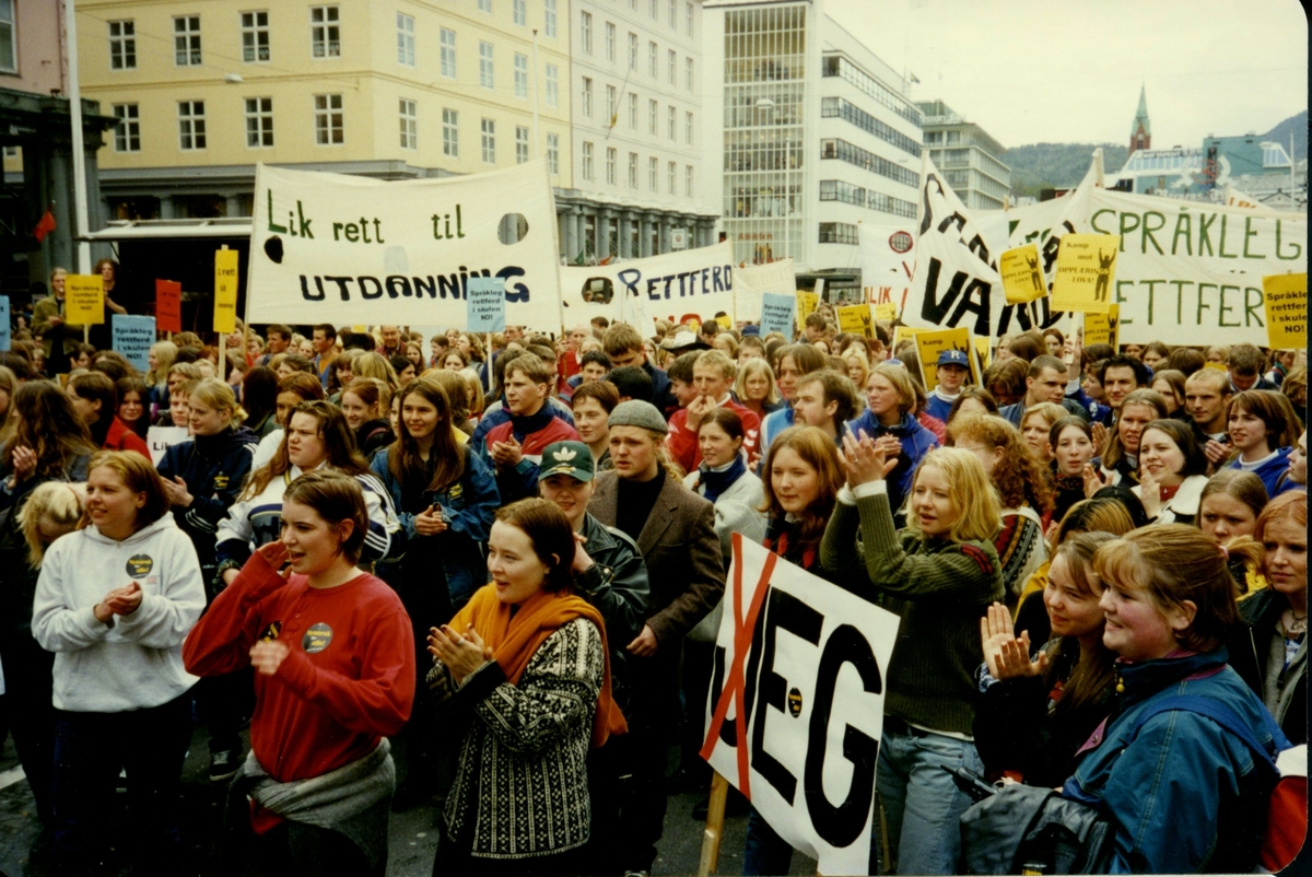 Fotografi frå arkivet til Norsk Målungdom. Biletet er teke i Bergen under Aksjon for språkleg rettferd i skulen (AFSRIS) i 1997. AFSRIS var eit samarbeid mellom Norsk Målungdom, Norsk Elevorganisasjon og Norsk Gymnasiastsamband, som arbeidde mot å fjerne retten til læremiddel på nynorsk. Det er uvisst kven fotografen er.

Dette er eit av fleire foto frå arkivet til Norsk Målungdom. For innsyn ta kontakt med Nynorsk kultursentrum.