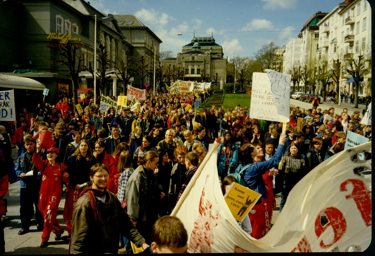Fotografi frå arkivet til Norsk Målungdom. Biletet er teke i Bergen under Aksjon for språkleg rettferd i skulen (AFSRIS) i 1997. AFSRIS var eit samarbeid mellom Norsk Målungdom, Norsk Elevorganisasjon og Norsk Gymnasiastsamband, som arbeidde mot å fjerne retten til læremiddel på nynorsk. Det er uvisst kven fotografen er.

Dette er eit av fleire foto frå arkivet til Norsk Målungdom. For innsyn ta kontakt med Nynorsk kultursentrum.