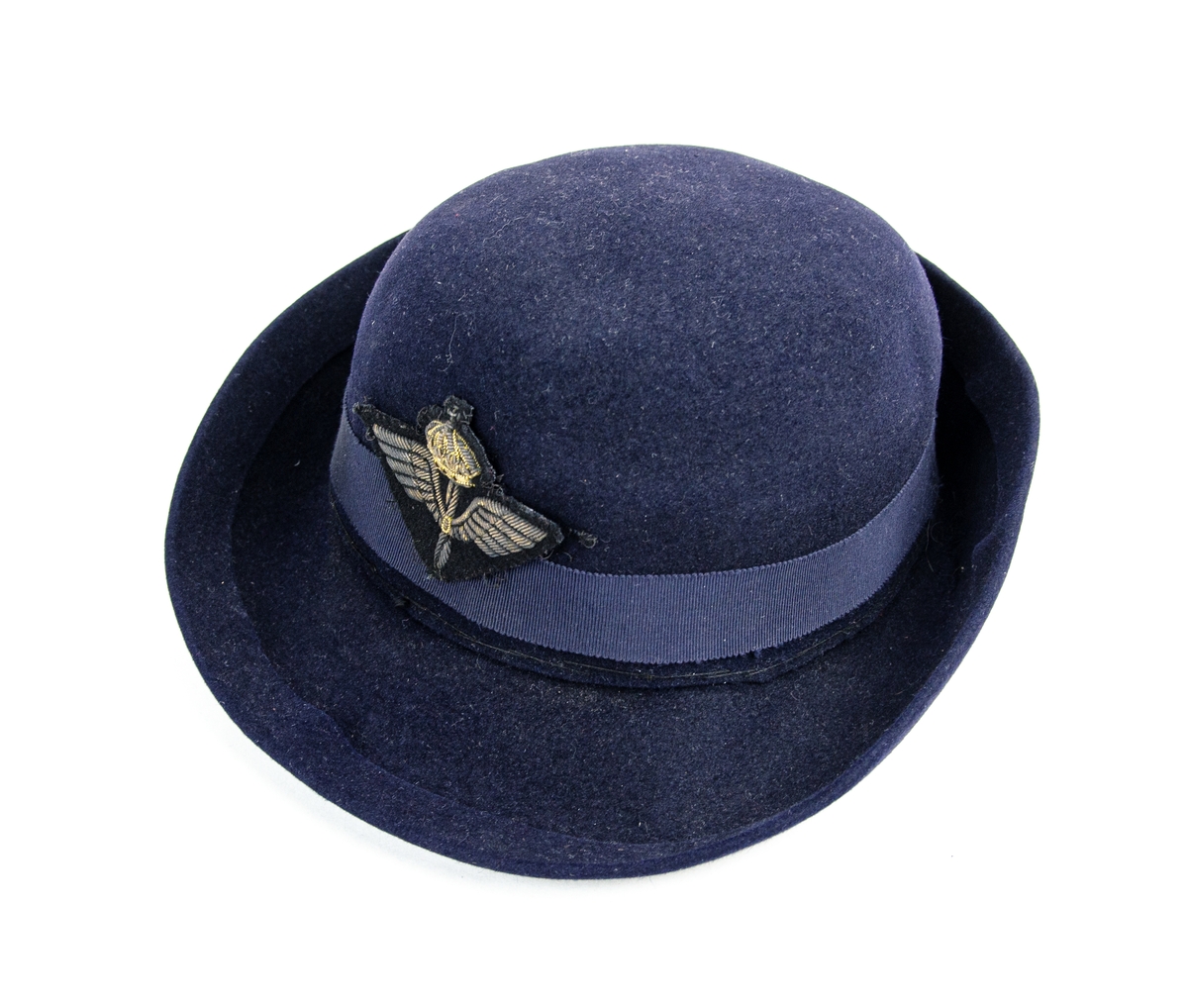 Hatt tillverkad i mörkblå filt, rund kullig med brätte. Försedd med mörkblått ripsband samt flygvapnets emblem i kantiljbroderi. 
På insidan ett band med texten: "RUNE" i rött.
Hatten är en del av flyglottauniform bestående av: Jacka, kjol, kappa och hatt.