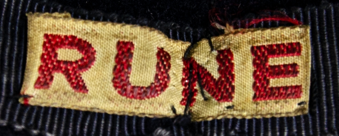 Hatt tillverkad i mörkblå filt, rund kullig med brätte. Försedd med mörkblått ripsband samt flygvapnets emblem i kantiljbroderi. 
På insidan ett band med texten: "RUNE" i rött.
Hatten är en del av flyglottauniform bestående av: Jacka, kjol, kappa och hatt.