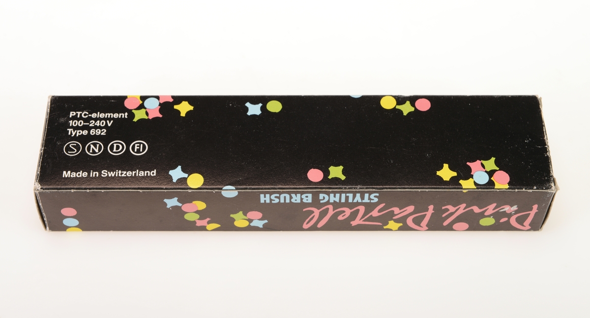 En stylingbørste av typen "Pink Pastell" i originalemballasje. Børsten har smal sylindrisk form av rosa plast. I den ene enden er det festet en svart elektrisk ledning. Børstedelen er sylindrisk med avrundet tupp og med pigger av plast. Det er rader med 15 pigger på hver rad. Esken er av kartong og har svart bunnfarge. Det står "Pink Pastell" på alle sider. på forsiden er det tegning av børsten. På undersiden av esken er det produktinformasjon. Det er spredt "konfetti" jevnt over hele esken i fargene rosa, lys blått, lys grønt og gult. I esken ligger det en bruksanvisning/garantibevis på norsk, finsk, svensk og dansk.