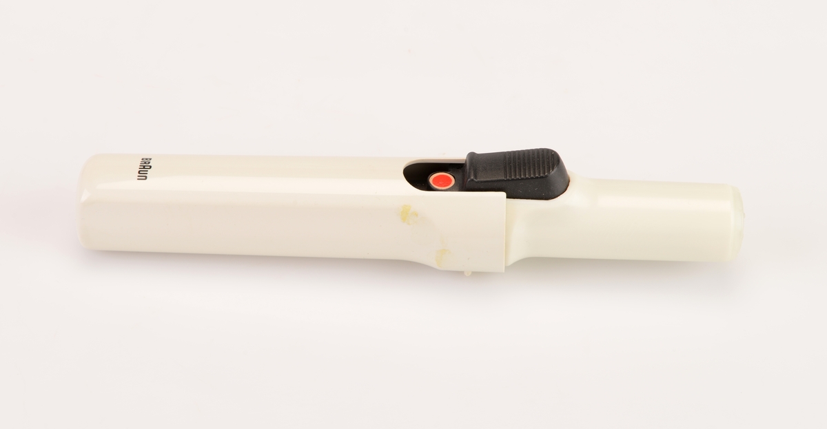 En krølltang av typen "Braun independent curler" i originalemballasje. Esken er av papp og har tekst/illustrasjoner på alle sider. Det er blant annet flere fotografier av krølltangen asmt fotografier som visr at den tar liten plass og at man kan fikse håret når som helst og hvor som helst. Esken åpnes på toppen og henger fast i bakkanten på esken. På undersiden av lokket er det informasjon og illustrasjoner som informerer om bruk av krølltangen. I eskdedelen er det et "utstillingsvindu" delvis dekket med plast. Krølltangen ligger i en burgunderfarget plastinnsats som er formet etter tangens deler. Krølltangen er to deler og laget av hvit plast og svart metall. på tangens håndtak er det en knapp somtrykkes ned og da går en del av tangen opp lsik at man kan rulle håret opp. Til hører det også til en beskyttelseshette av hvit plast. Gassbeholderen mangler.