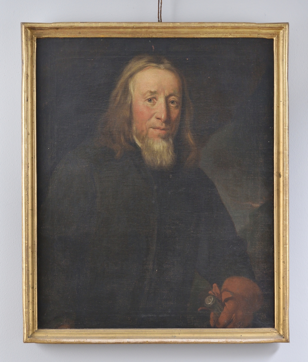 Porträtt av Erik Ersson. Midjestycke åt höger. Ersson med gråsprängt hår, svart tillknäppt rock och brun handske på vänsterhand, vilken greppar den andra handsken samt en käpp. Käppen med silverknapp varpå "E.E.S" står skrivet. 