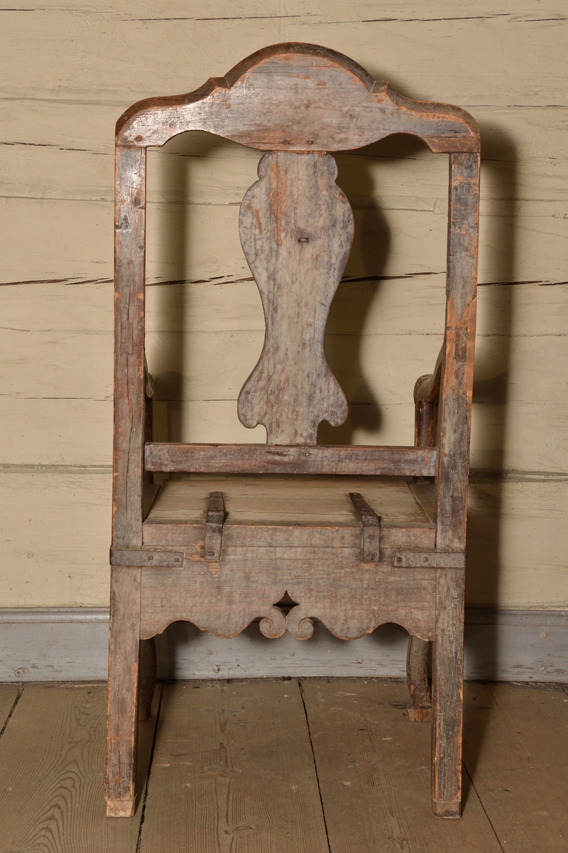 Stol tillverkad i björk och furu, rokokostil. Rak, delvis genombruten rygg med balusterformad ryggbricka. Krönet av stolsryggen med skuren ornering i form av voluter och snäcka. Lätt svängda armlän med dekorativt skurna avslut i form av voluter och akantusblad. Rak ostoppad sits i två delar, överst lucka med järnbeslag vilken går att fälla upp, under en sits med utskuret hål för placering av nattkärl. Bred sarg med skuren dekor i böljande vågmönster, samt var sida med genombrutet stjärnformat hål. Stolen vilar på fyra ben, de bakre enkla och raka, och de främre lätt svängda med skuren mussla.