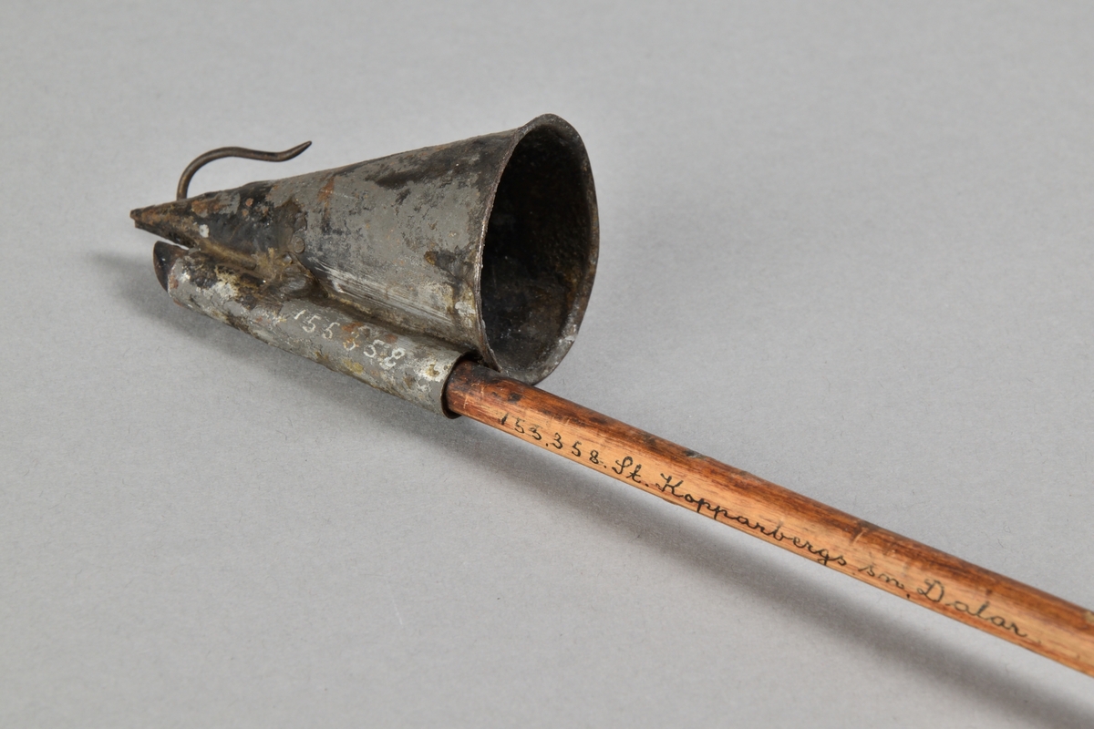 Ljussläckare av järnbläck med långt skaft i trä. Trattformad ljussläckare med järnkrok. Skaft med rundat avslut. 