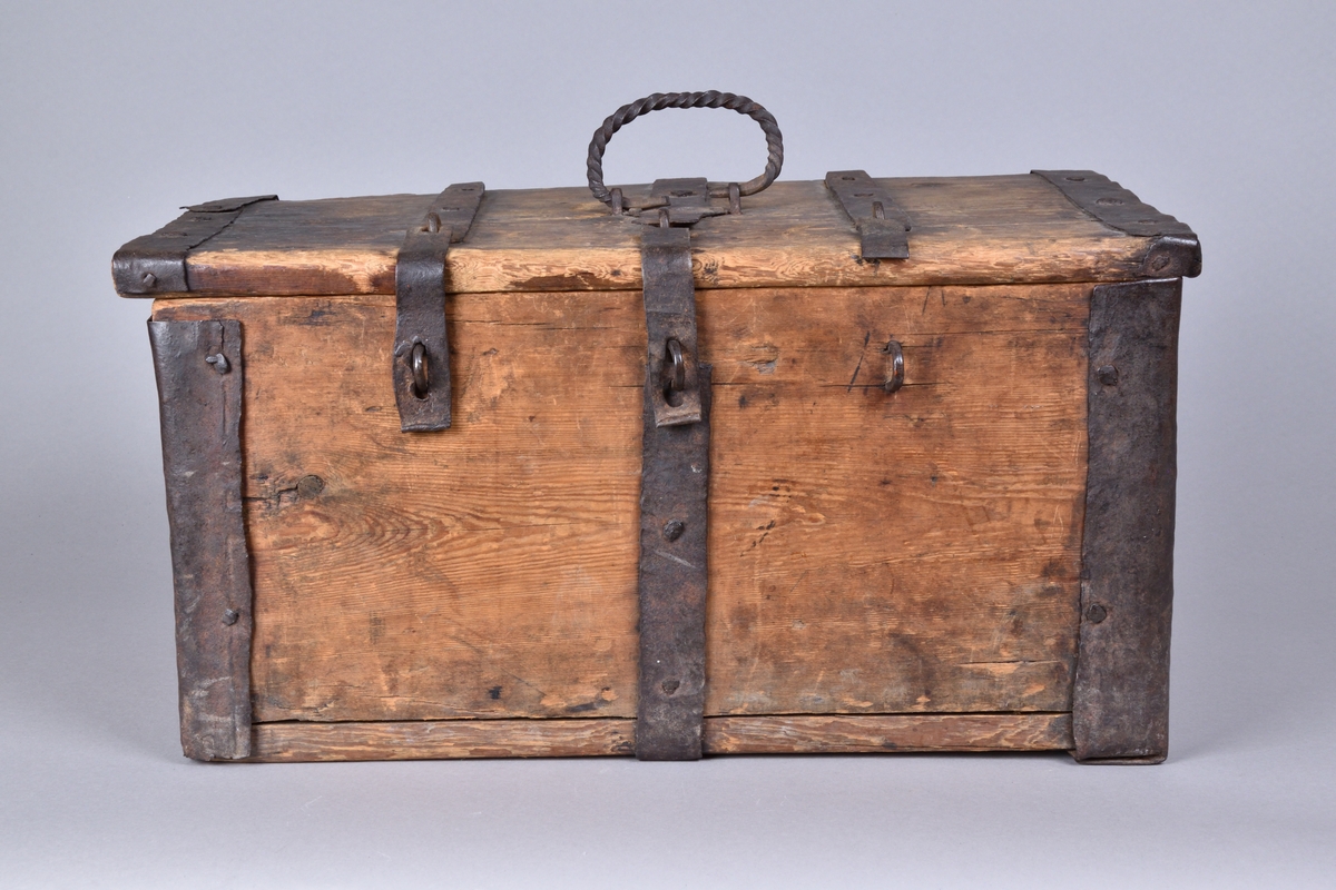 Skrin av trä tillverkat i trä, med lock. Rektangulär och djup, med utanpåliggande järnbeslag. På ovansidan handtag av spiralvridet järnband. Lockets insida med stämpel.


Funktion: Förvaring av föremål