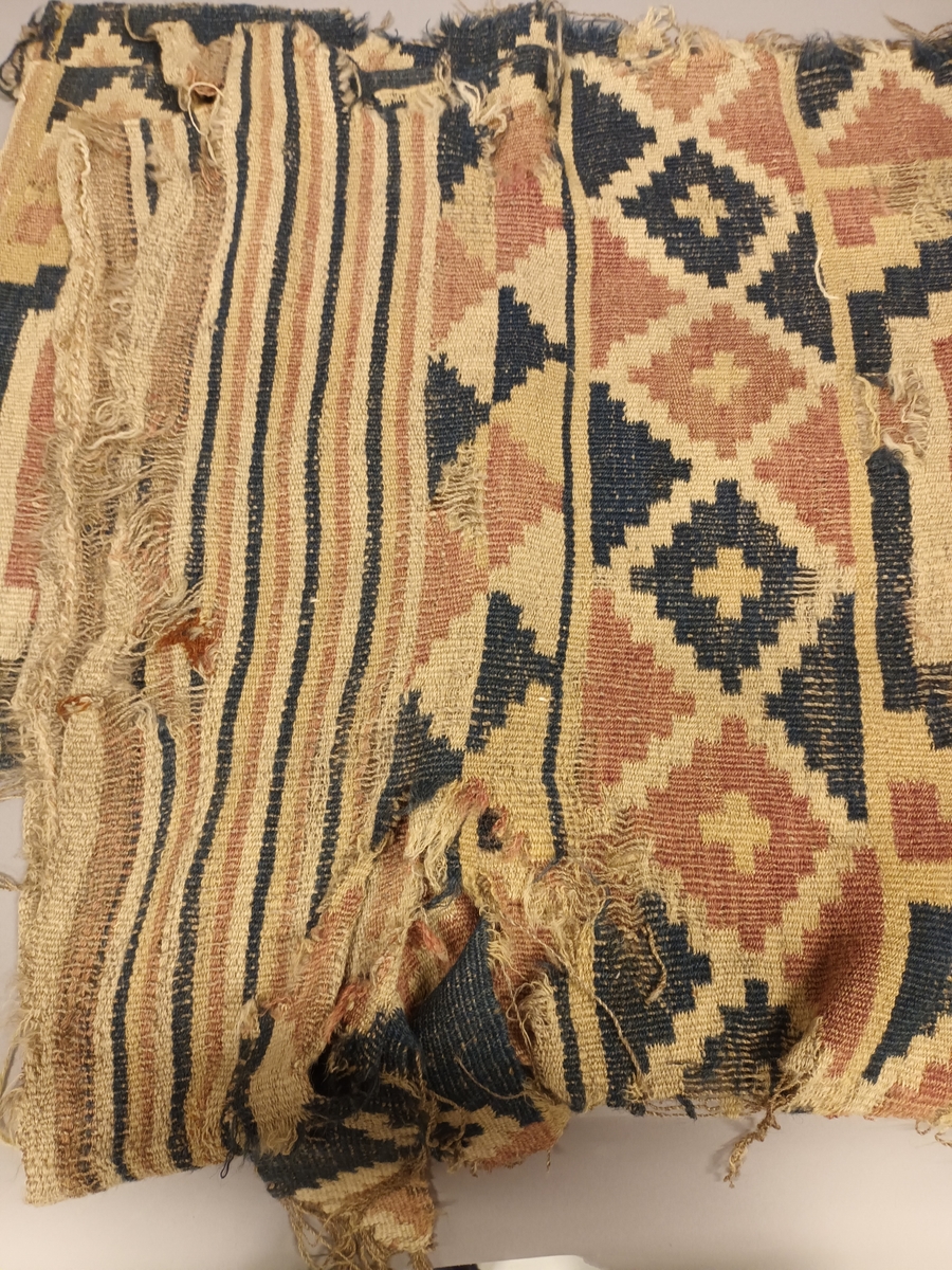 Ruteåkle i smett med enkle slyng over fire tråder.Truleg heimspunne og heimefarga garn både i renning og innslag. To tråds ullgarn, relativt hardt spunne. Fire åttebladsroser, ruteborder og striper nederst. Smal fald i begge korsidene. Teppet er særs slitt og falma.