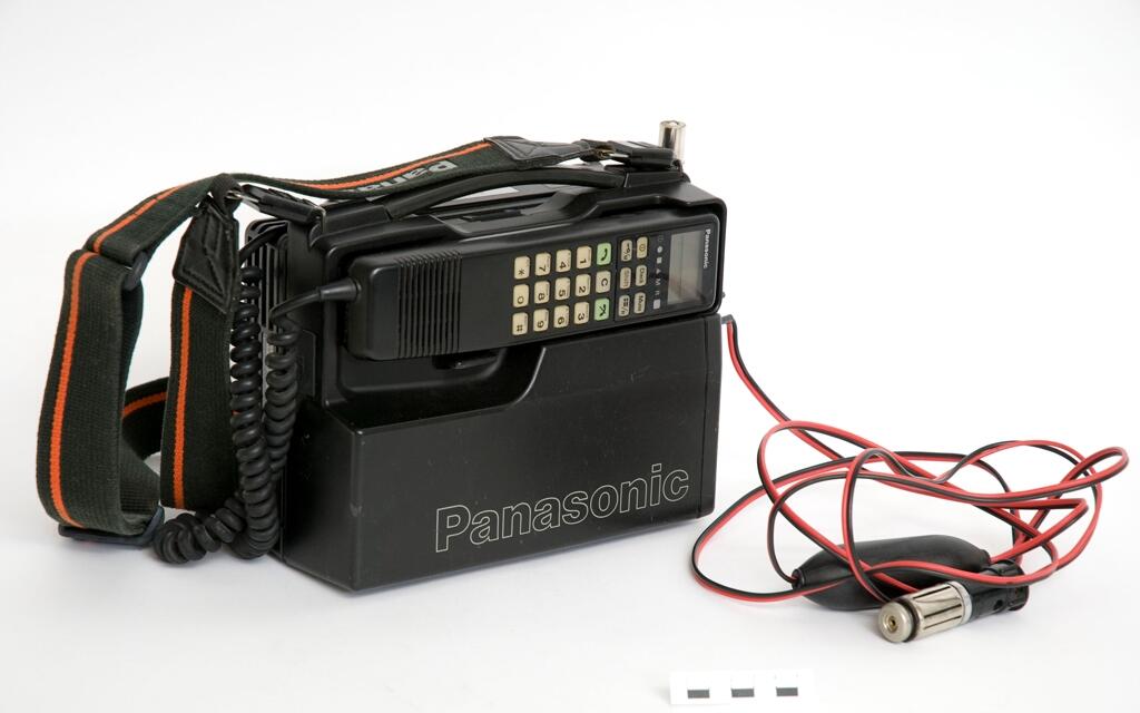 Mobiltelefon Panasonic med tillhörande nätaggregat (se M26070_B).