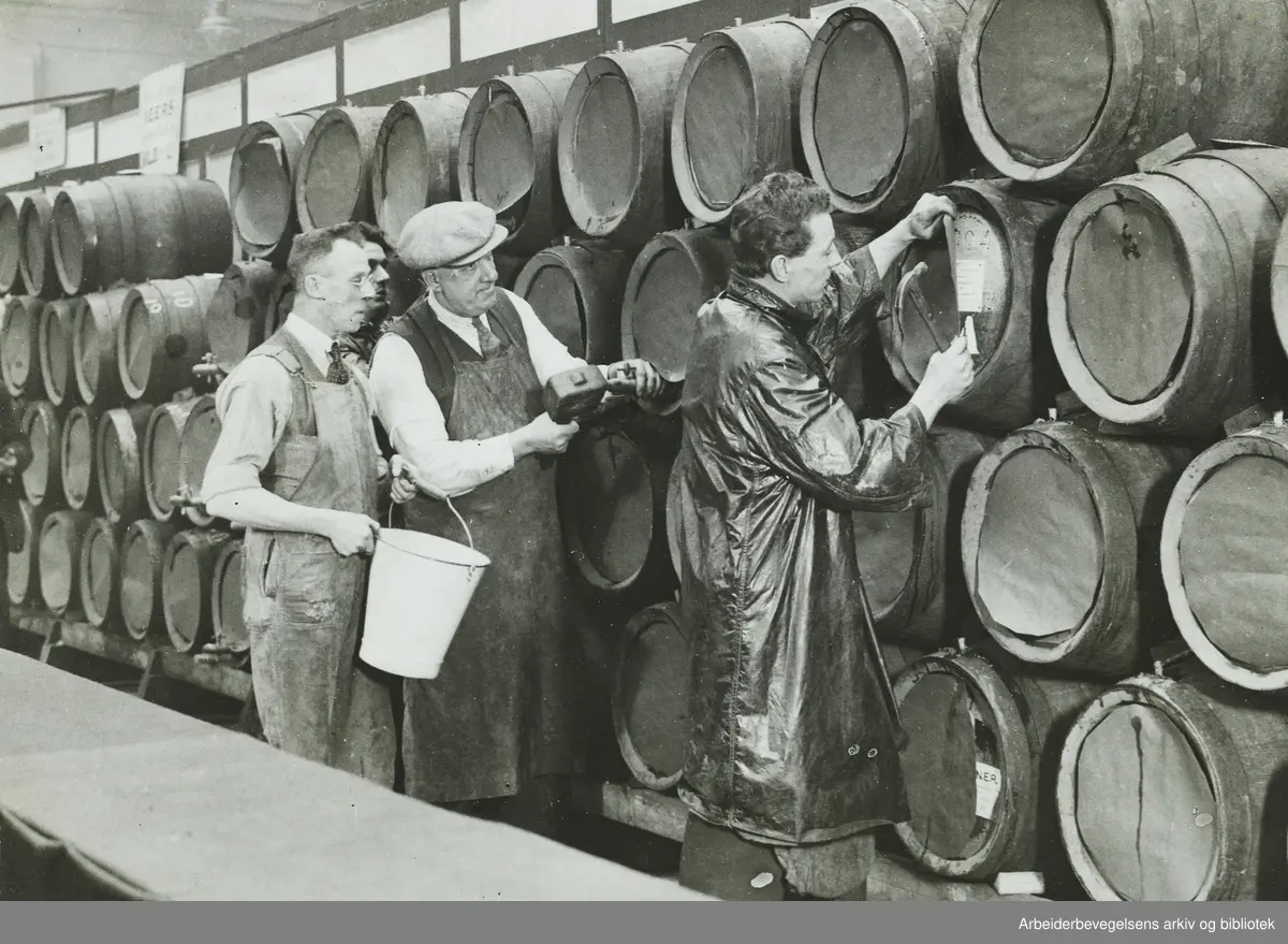 Den årvisse bryggeriutstillingen i Royal Agricultural Hall, London. På bildet dekkes firmamerkene på øltønnene til før prøvesmaking og utkåring av årets øl finner sted. Arbeidermagasinet. Oktober 1932