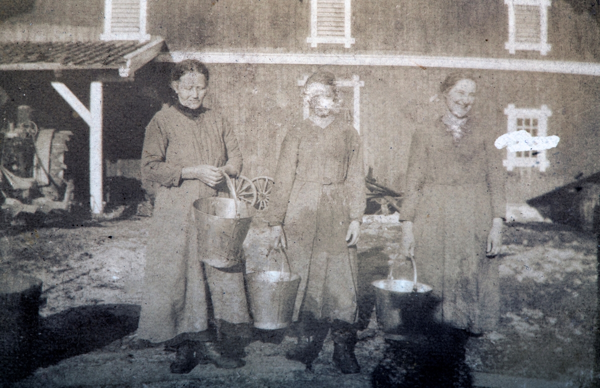 Karset (63/1). Lina, Anna og Julie med bøtter. Traktor med jernhjul til venstre innunder låven. Den gamle låven brant etter krigen.