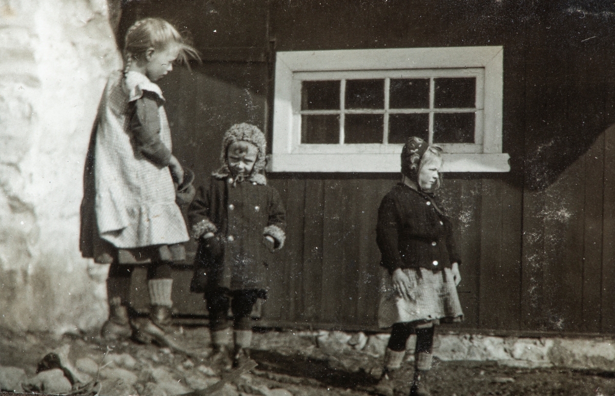 Karset (63/1). Jenter ved husvegg. Fra venstre Olea (f.1904), Pauline (f. 1906) og Ingeborg (f.1910) Karset. Døtre av Helga og Helge Karset.