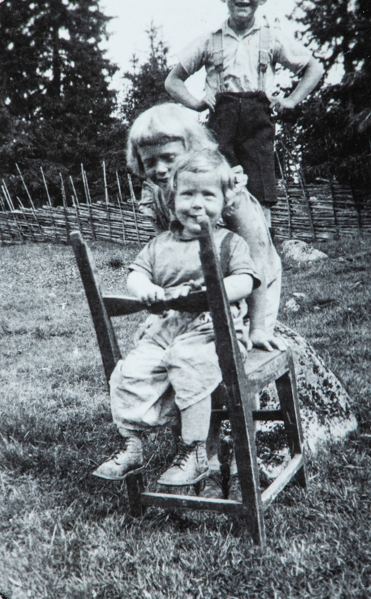 Øvre Tomter (60/1). Kristen Prestrud, Helga Prestrud og Helge Andreas Prestrud (halvt skjult) i lek med stol.