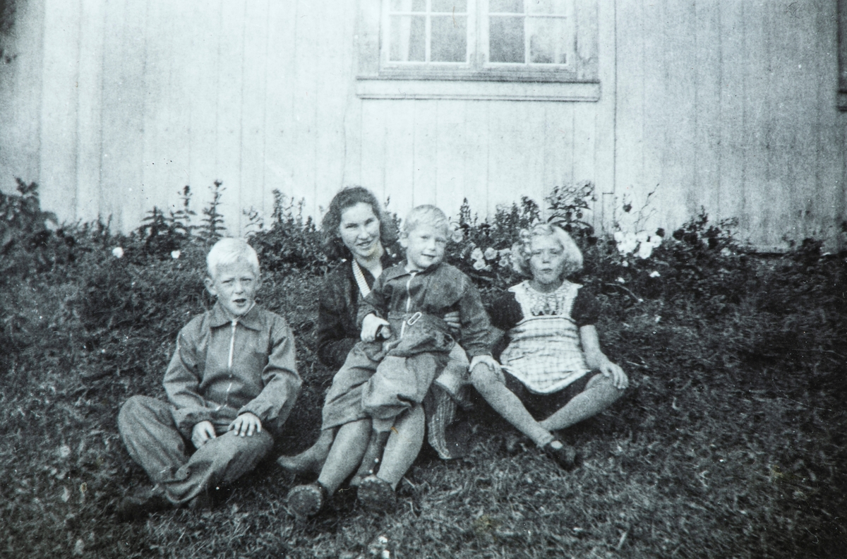 Øvre Tomter (60/1). ca. 1940. Barna Helge Andreas, Kristen og Helga Prestrud i husveggen på Øvre Tomter. Hushjelp/ barnepike sitter bak.