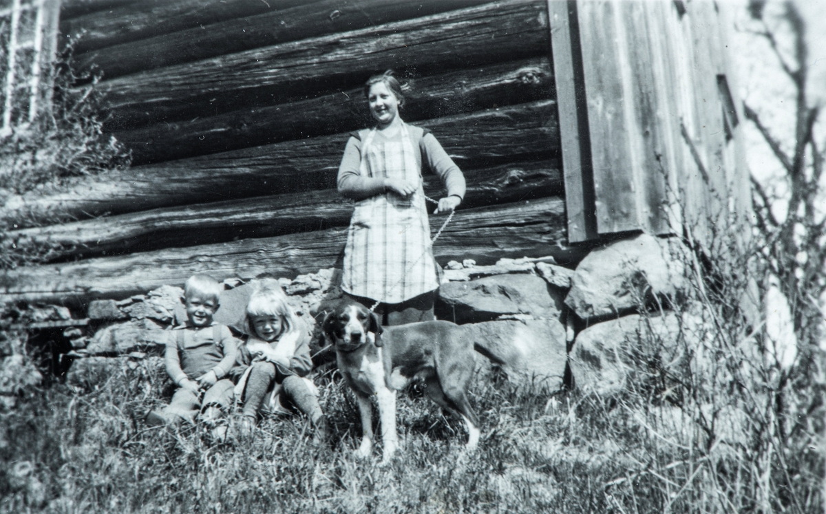 Øvre Tomter (60/1). Hushjelpa Marie Haraldsen fra Nordbygda i Løten, barna Helge Andreas og Helga Prestrud ved den gamle føderådsbygningen på Øvre Tomter.