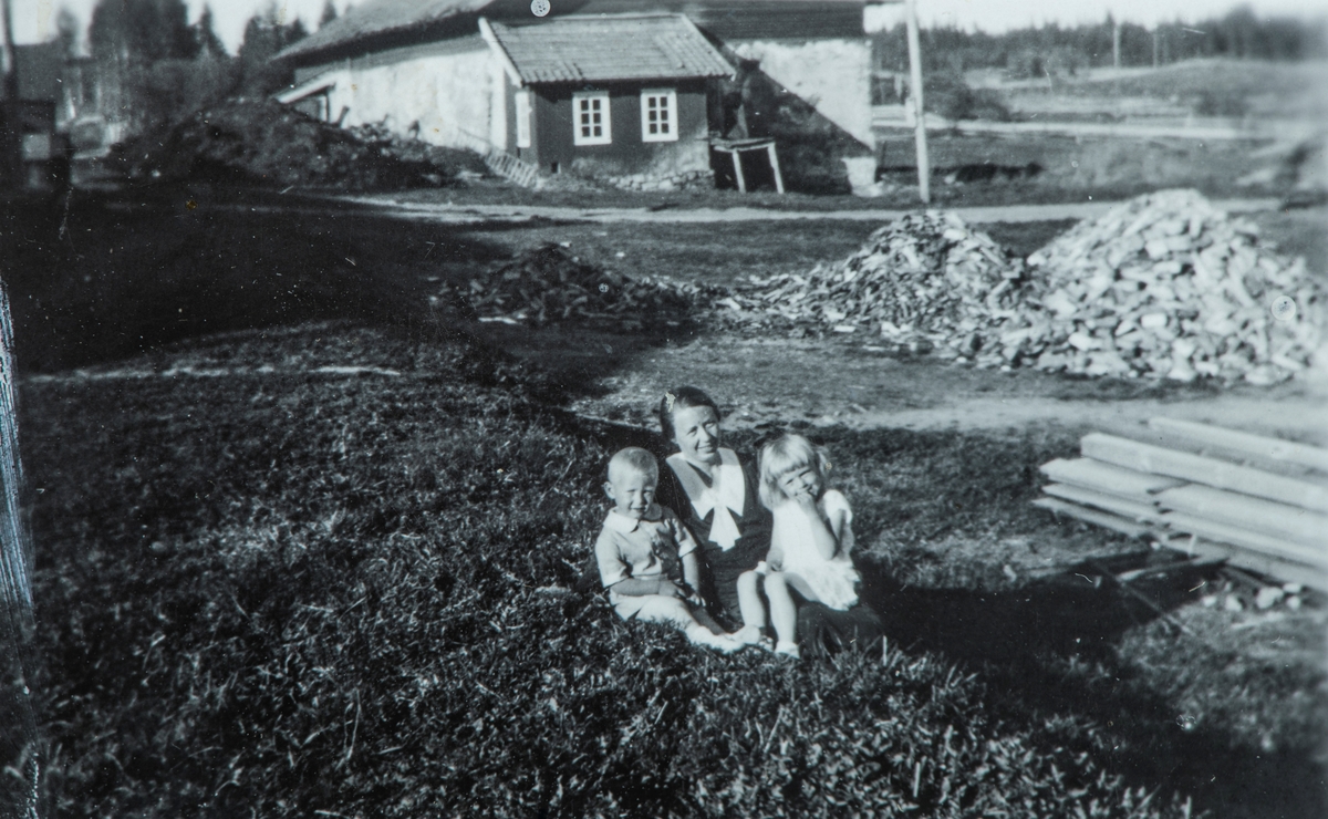 Øvre Tomter (60/1). Olea Lunde (f. Karset), Helge Andreas og Helga Prestrud på tunet på Øvre Tomter. Gammelfjøset med påbygd hønsehus i bakgrunnen. Ca. 1935.