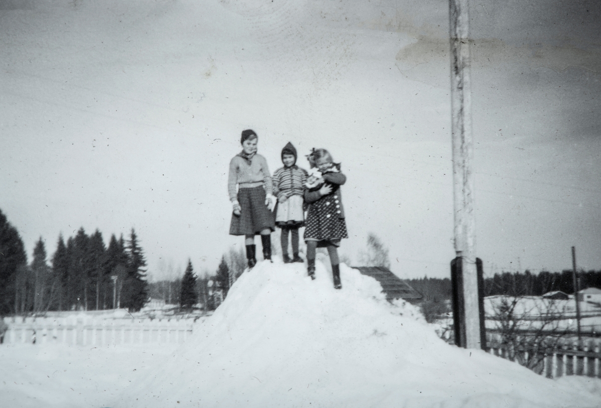 Øvre Tomter (60/1.) 3 Barn på toppen en snøhaug. Ragnhild Prestrud og søstrene Hagen som bodde i drengestua på Øvre Tomter. Ragnhild til høyre. Vinter.
