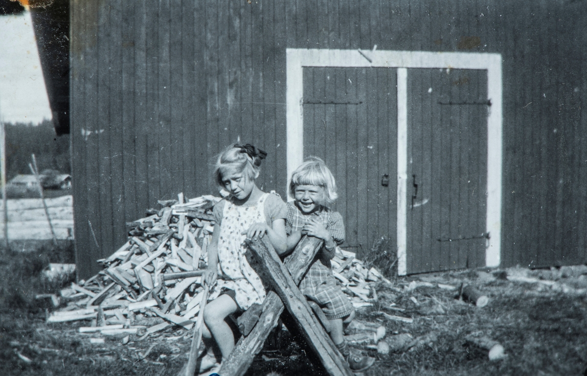 To jenter sitter på en sagekrakk. Helga Prestrud til høgre.