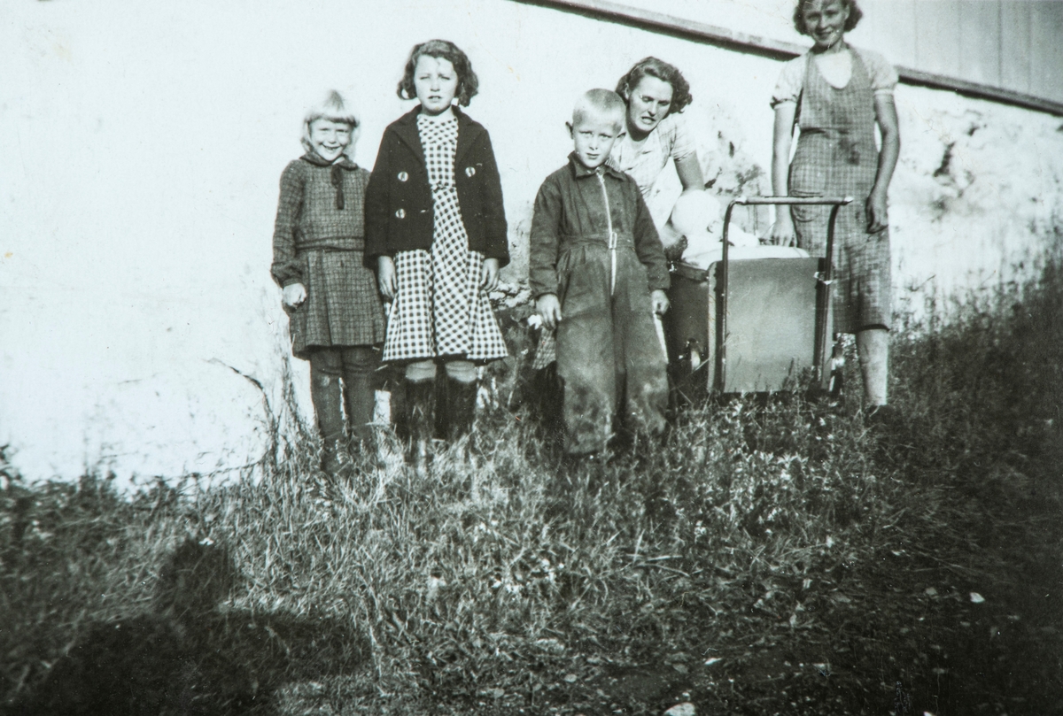 Øvre Tomter (60/1). Barn i husveggen på hovedbygningen på Øvre Tomter ca. 1938. Fv. Helga Prestrud,  ?, Helge Andreas Prestrud, ?, Kristen Prestrud i barnevogn, ?..