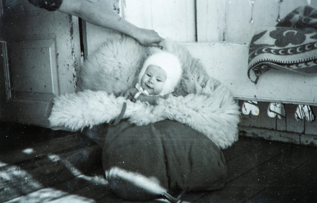 Øvre Tomter (60/1). Ragnhild Prestrud sittende i saueskinnspose ute på verandaen på Øvre Tomter 1947.