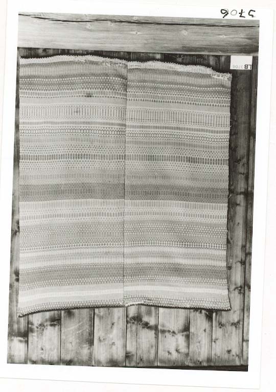 Krokbragdteppe kanta med ullstoff i kortendane. enning i bommull. Innslag av ullgarn. Plantefarga garn i innslag. Skjøyt p midten, bordane stemmer godt overens i skøyten.