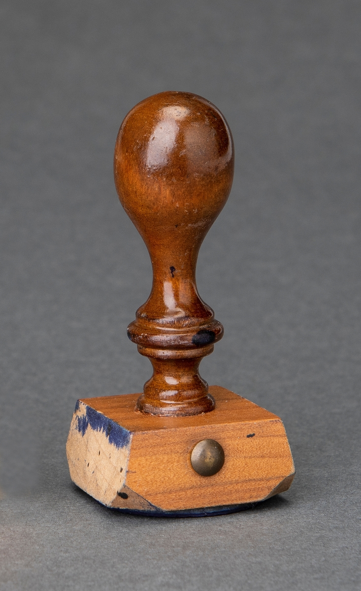 Stempel i lakkert tre. Selve stempelet har "Trondhjemsrosen" i midten omringet av teksten "Byen skal hete Trondhjem", slagord for striden om byen Trondheim sitt navn i årene 1929 og 1930.