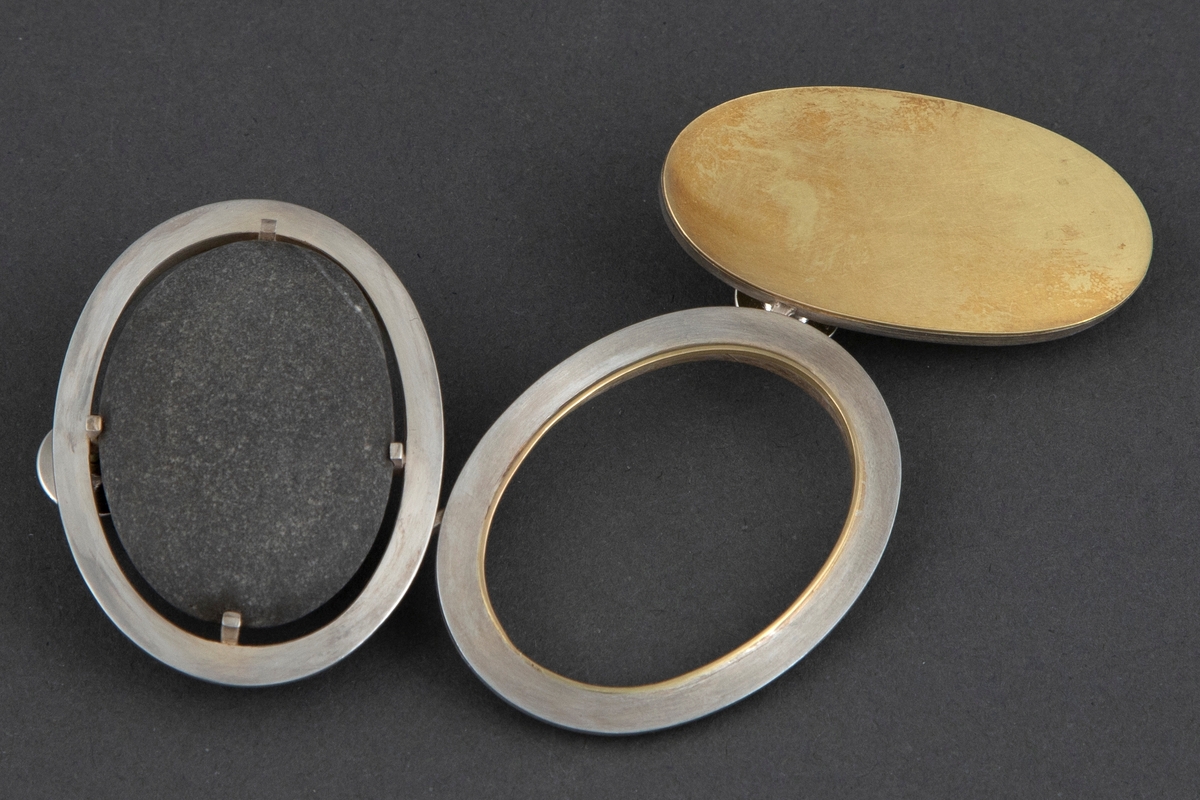 Brosjen er satt sammen av tre ovale ringer i børstet sølv og gull. Sølvringen holder på en svart rullestein. Åpen ring i midten av sølv med en liten gullkant i veggene. Ringen til høyre har en heldekkende gullplate med sølvvegg. De tre ringene er festet sammen på baksiden med sølvstaver. Brosjen har to pinfester. På baksiden av gullplaten er det inskribert signaturen Millie Behrens.