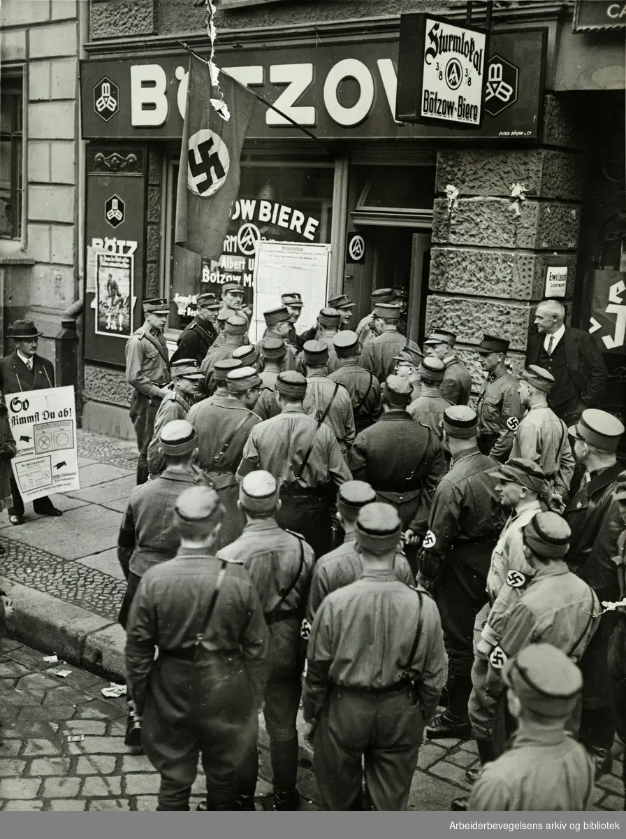 Tyske brunskjorter - SA-soldater (Stürm-Abteilung) køer foran en ølhall i Berlin, et såkalt "Sturmlokal". Reklame for Bötzow-biere. Valgplakat. Antatt 1933.