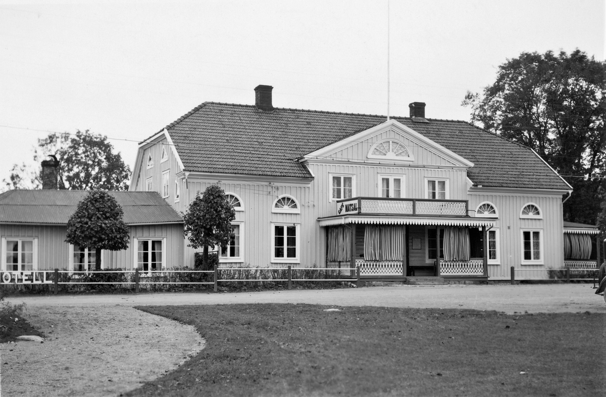 Gästgivaregården i Torup. Längst till vänster står det Hotell på staketet och på balkongens gavel annonseras Café och Matsal. Byggnadens verandor är försedda med randiga gardiner och har liksom balkongräcket sirliga figursågade dekorer. Framträdande i fasaden är de stora halvmåneformade fönstren (lunettfönster).