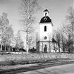 Högsjö kyrka. Exteriör, nya kyrkogården. Kyrkan invigdes 1789. Byggmästaren var Simon Geting från Sundsvall efter ritningar av Per Hagmansson bosatt i Sundsvall. Bildhuggaren till en del inredning är Pehr Westman från Hemsön. Predikstolen och altaruppsättningen i den nyklassicistiska stilen är Olof Hofréns arbete. Orgel tillverkades av J.G. Ek från Härnösand. Olof Hofrén fick i uppdrag att måla, ornera och förgylla orgelfasaden. Altartavlan föreställande korset på Golgatan är en målning av Sven Linnborg från början av 1900-talet.